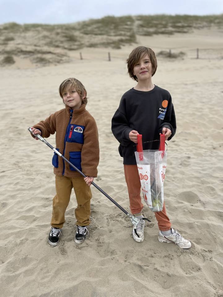 Foto van Mees (6 jaar) & Tijn (8 jaar) ruimen samen het strand op.